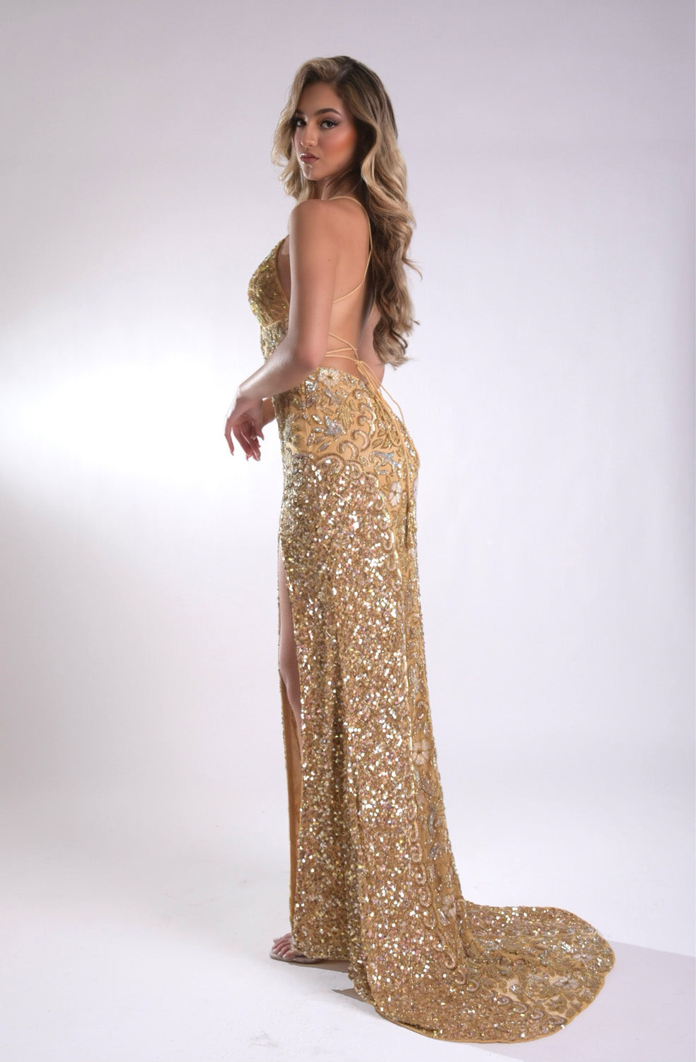 Jasz Couture 7968 Gold mermaid prom dress with a high slit and intricate sequins, back view.