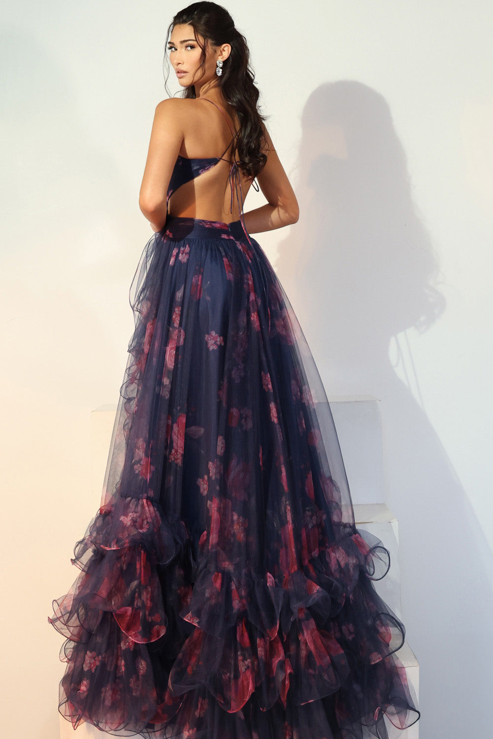 Jovani 45712 Dark blue floral prom dress with ruffled hem and open back design.