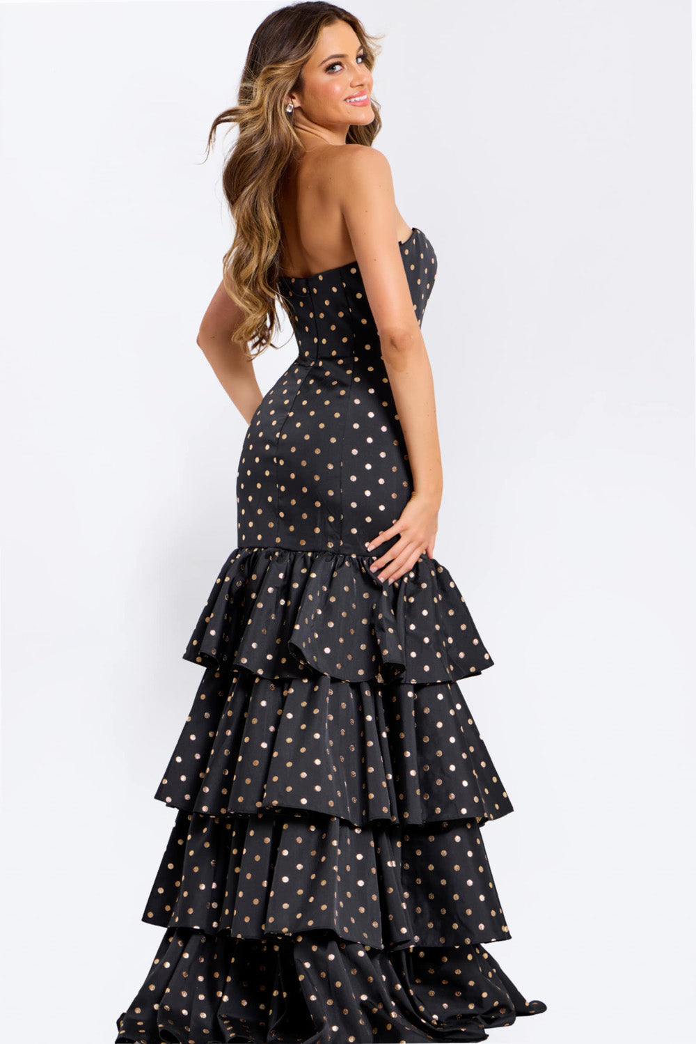 Jovani 49419 Black mermaid prom dress with gold polka dots and ruffled hem, back view.