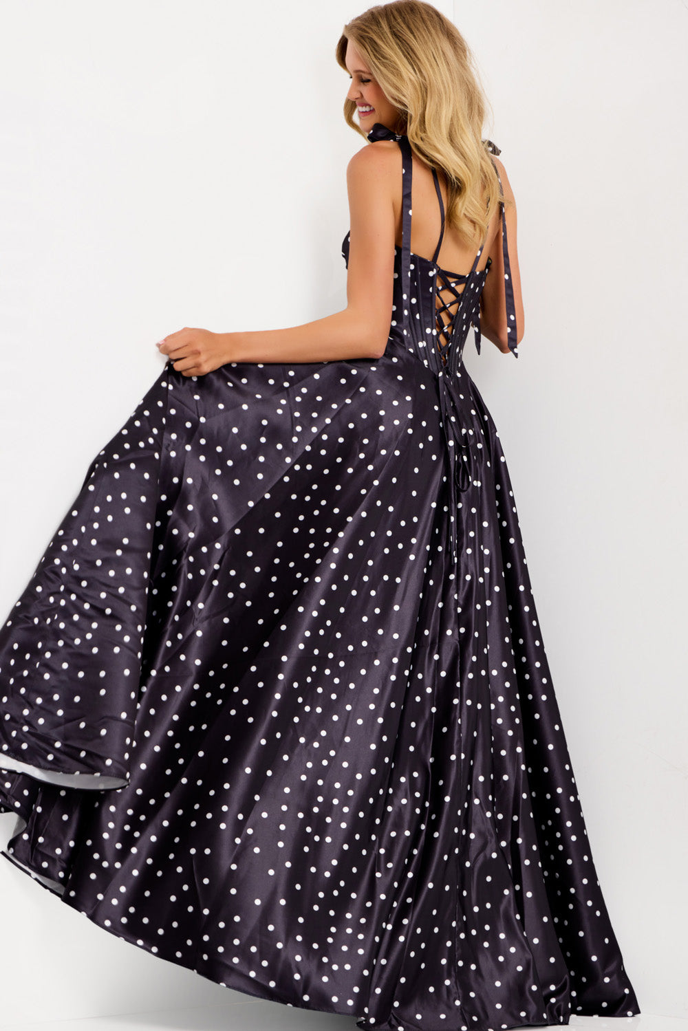 Jovani 49774 Navy polka dot prom dress with a lace-up back and flowing A-line silhouette.