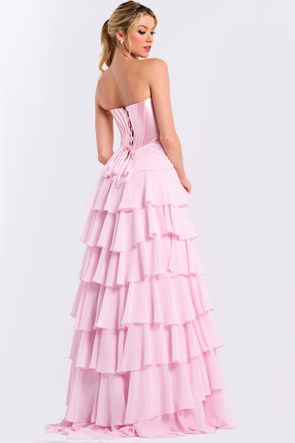 Jovani 50234 Pink strapless formal gown with a tiered skirt and lace-up back, back view.