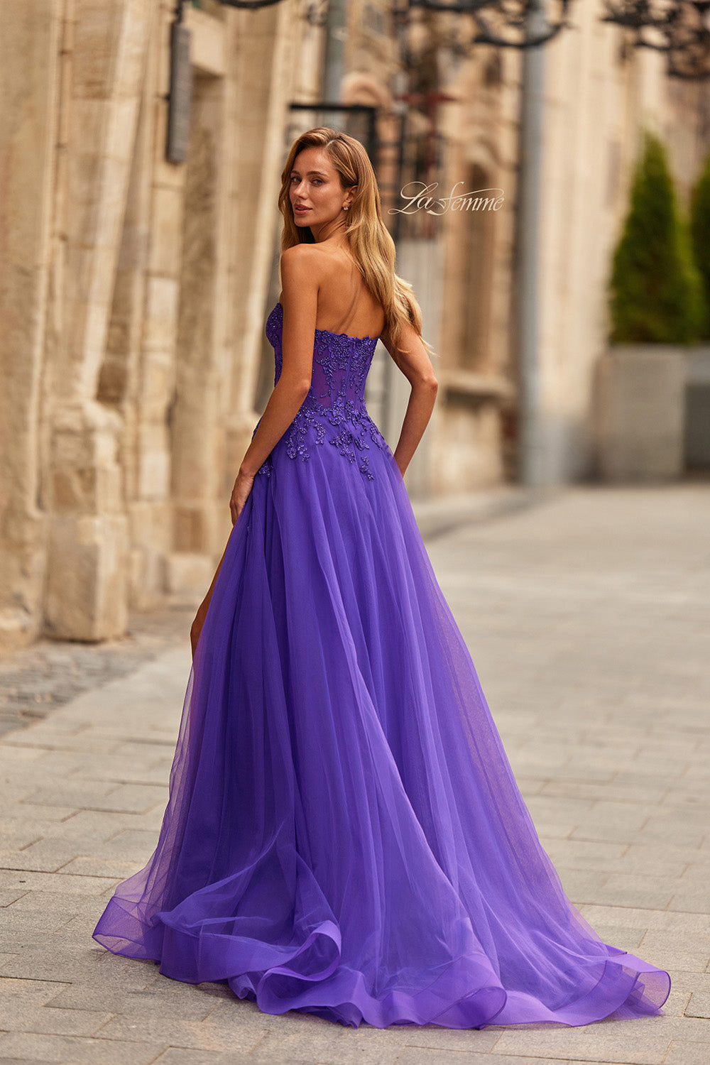 La Femme 33551 Royal purple A-line prom dress with lace detailing and a side slit, back view.