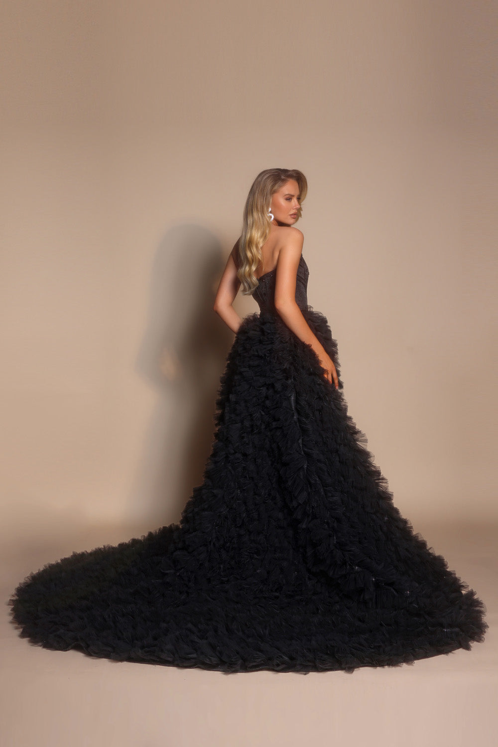 Portia and Scarlett PS26236 Black mermaid prom dress with ruffled train and corset back, side view.