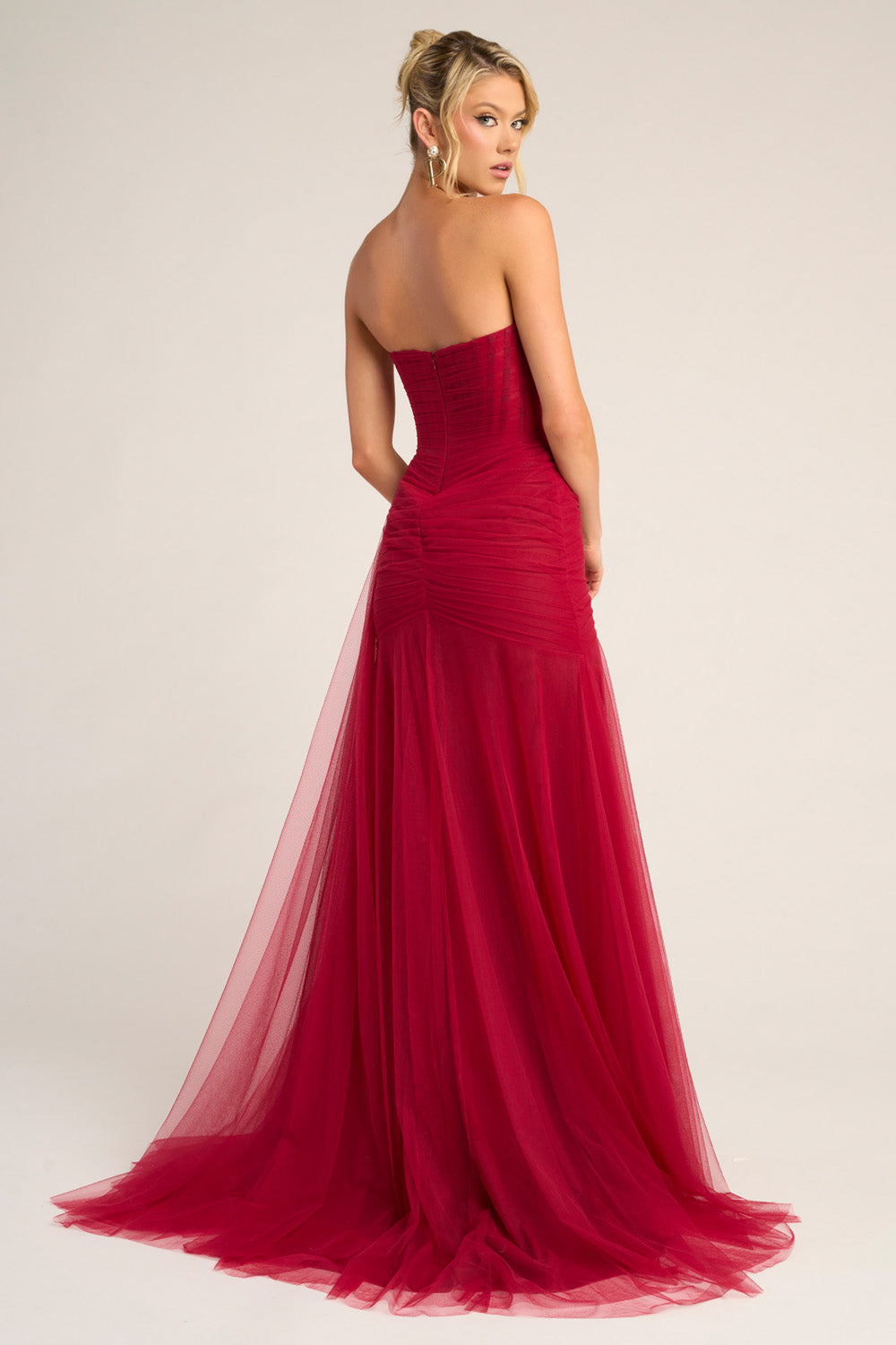 Portia and Scarlett PS26307e Red mermaid prom dress with a lace-up back and flowing tulle train, back view.