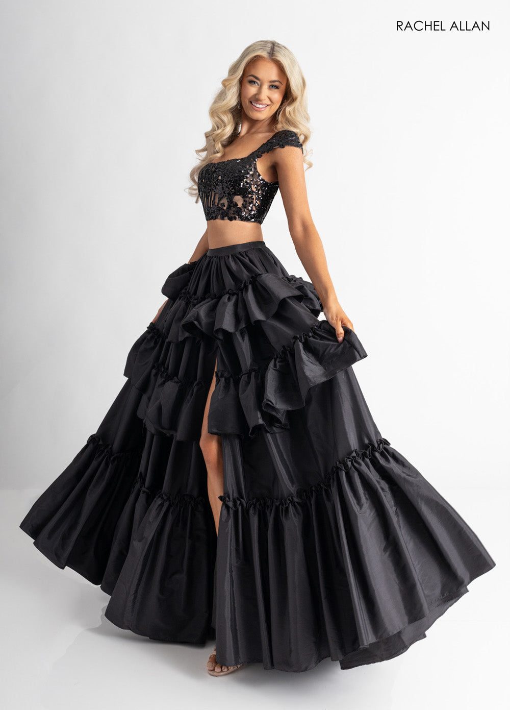 Rachel Allan 70966 Black mermaid prom dress with ruffled layers and a thigh-high slit.