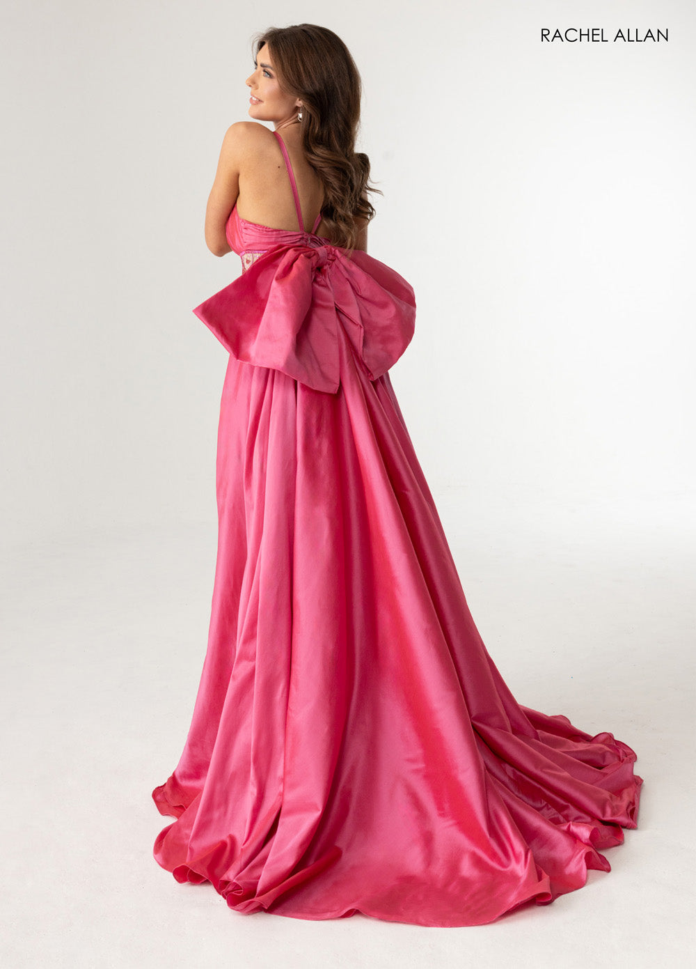 Rachel Allan 71016 Nude deep pink formal gown with a dramatic bow and flowing train, back view.