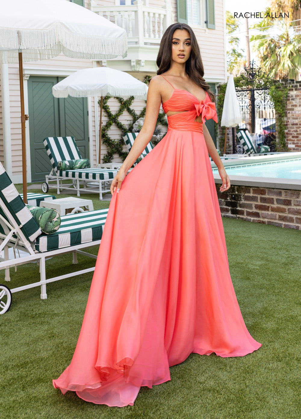 Rachel Allan 71050 Coral A-line prom dress with a bow detail and flowing chiffon fabric.