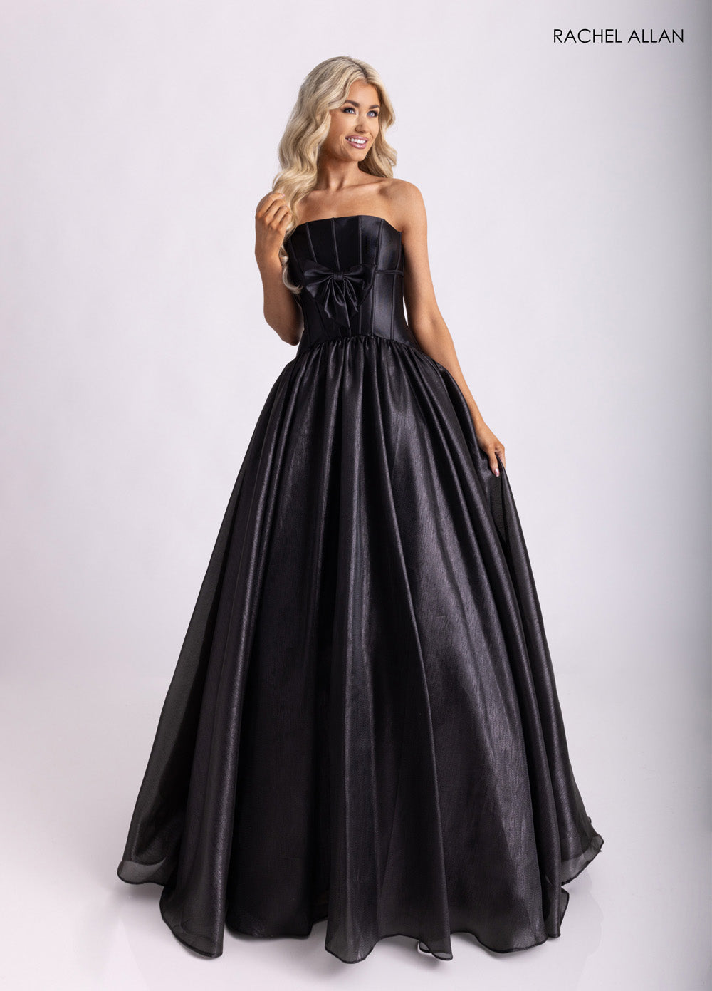 Rachel Allan 71060 Black ballgown prom dress with a strapless design and a bow detail at the waist.