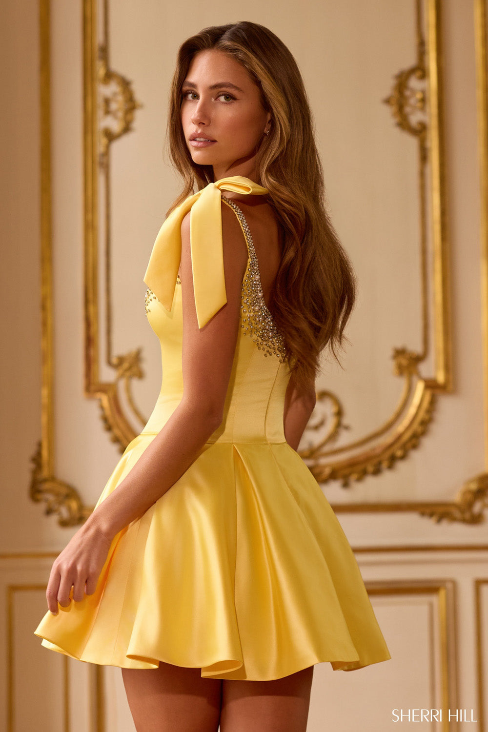 Sherri Hill 58066 yellow mini dress back view showing open back with crystal beading along straps and large bow detail at shoulder.