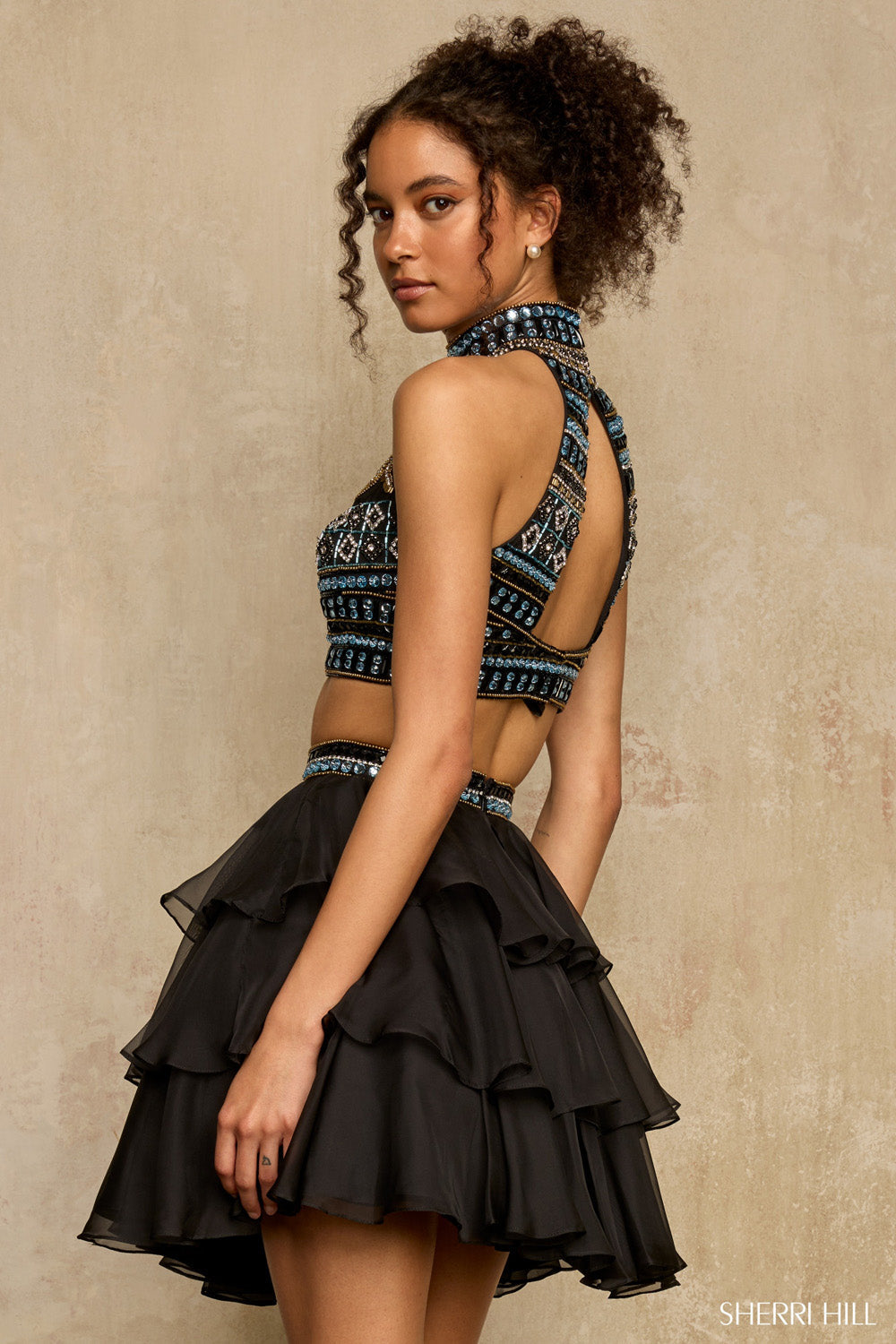 Sherri Hill 58399 black two-piece dress showing dramatic open racerback halter bodice and layered chiffon skirt, side profile view