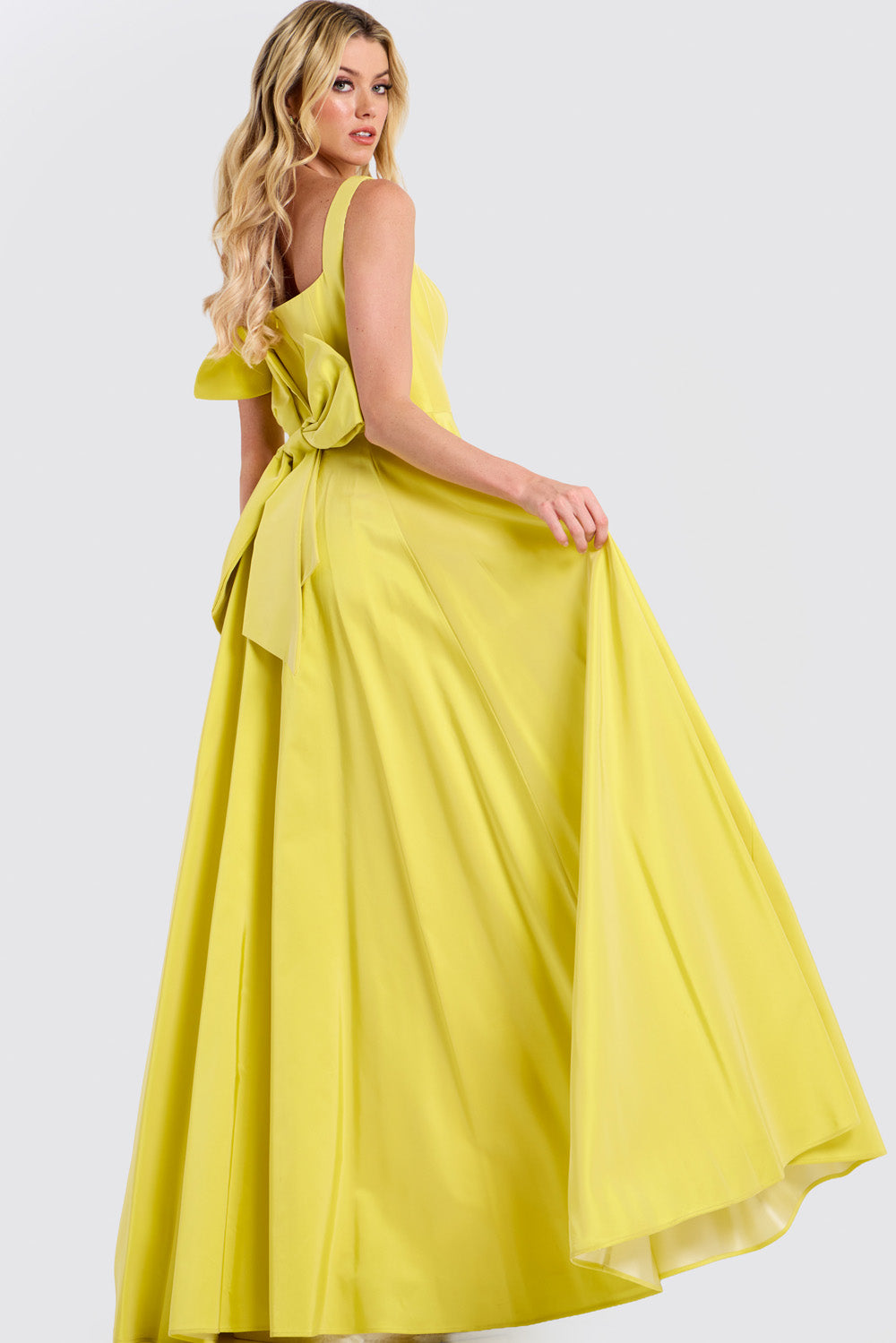 Jovani 47496 Yellow A-line prom dress with a dramatic bow and flowing skirt, back view.