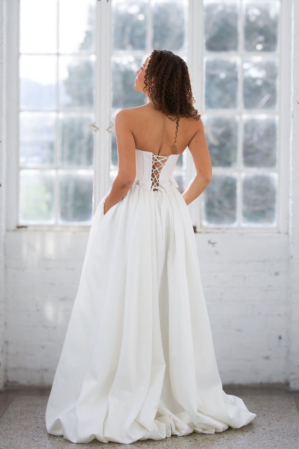 Miah Vega 24601 White A-line prom dress with a lace-up back and flowing skirt, back view.
