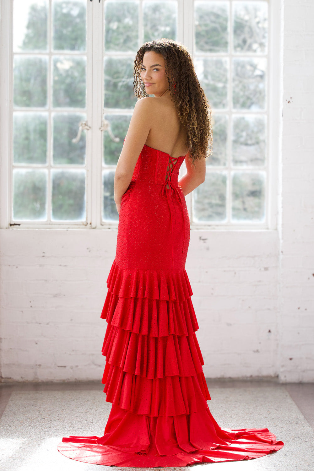 Miah Vega 24606 Red mermaid prom dress with tiered ruffles and lace-up back, back view.