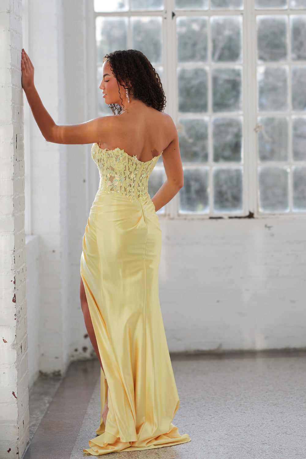 Miah Vega 24607 Yellow mermaid prom dress with lace-up back and thigh-high slit, back view.