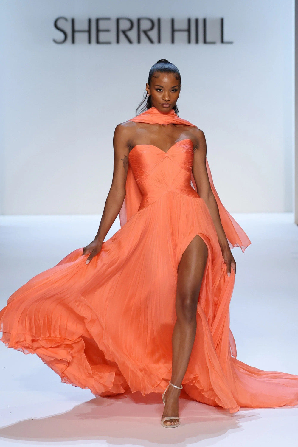 Sherri Hill 46715 coral pleated chiffon gown with sweetheart bodice, shoulder wrap and high front slit on runway