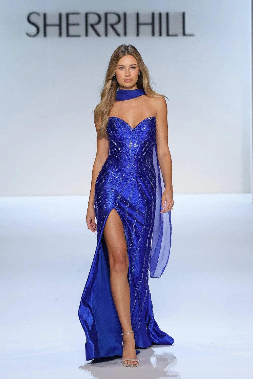 Sherri Hill 58757 Royal blue beaded strapless gown with flowing chiffon scarf and fitted silhouette on the runway