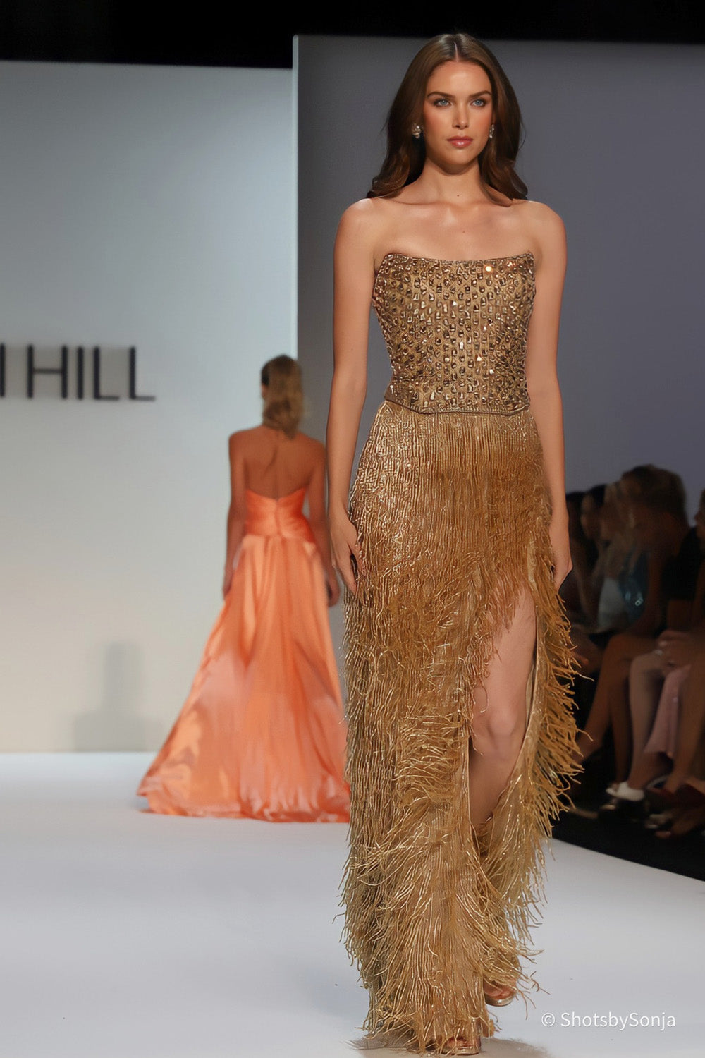 Sherri Hill 67236 gold beaded strapless gown with long metallic fringe skirt and front split walking the runway