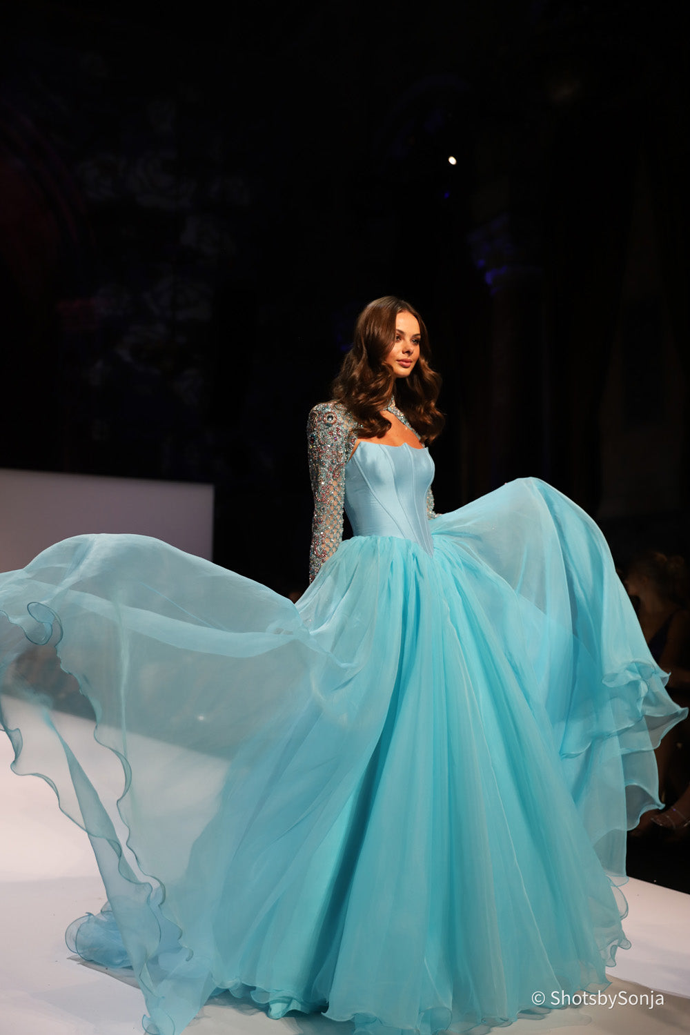 Sherri Hill 67345 aqua ballgown with beaded sleeves and flowing chiffon skirt caught mid movement