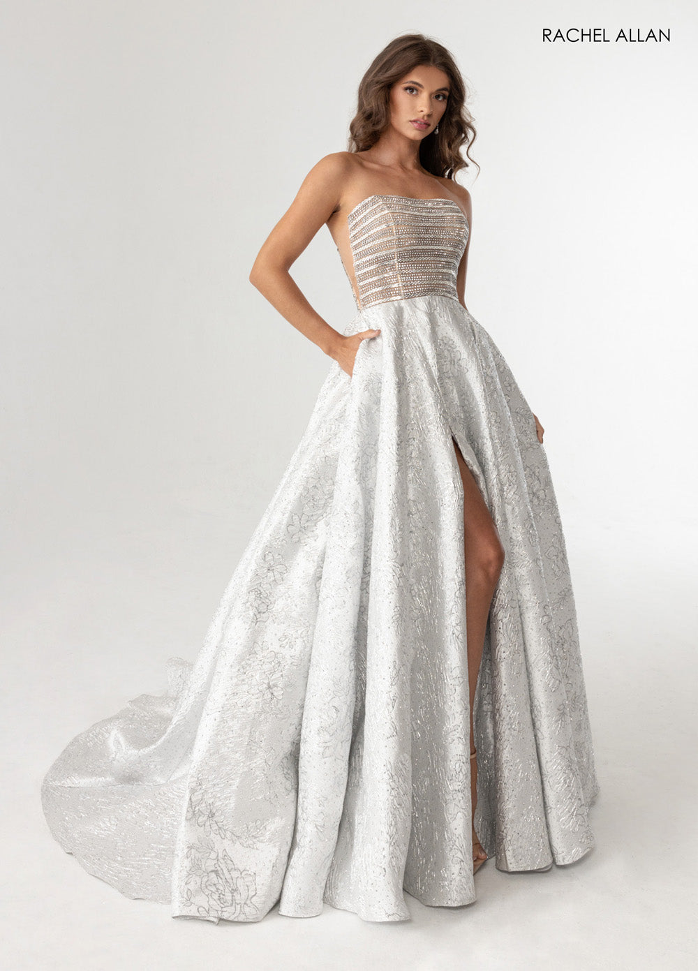 Rachel Allan 70956 Silver nude prom dress with a fitted bodice, crystal beading, and high slit.