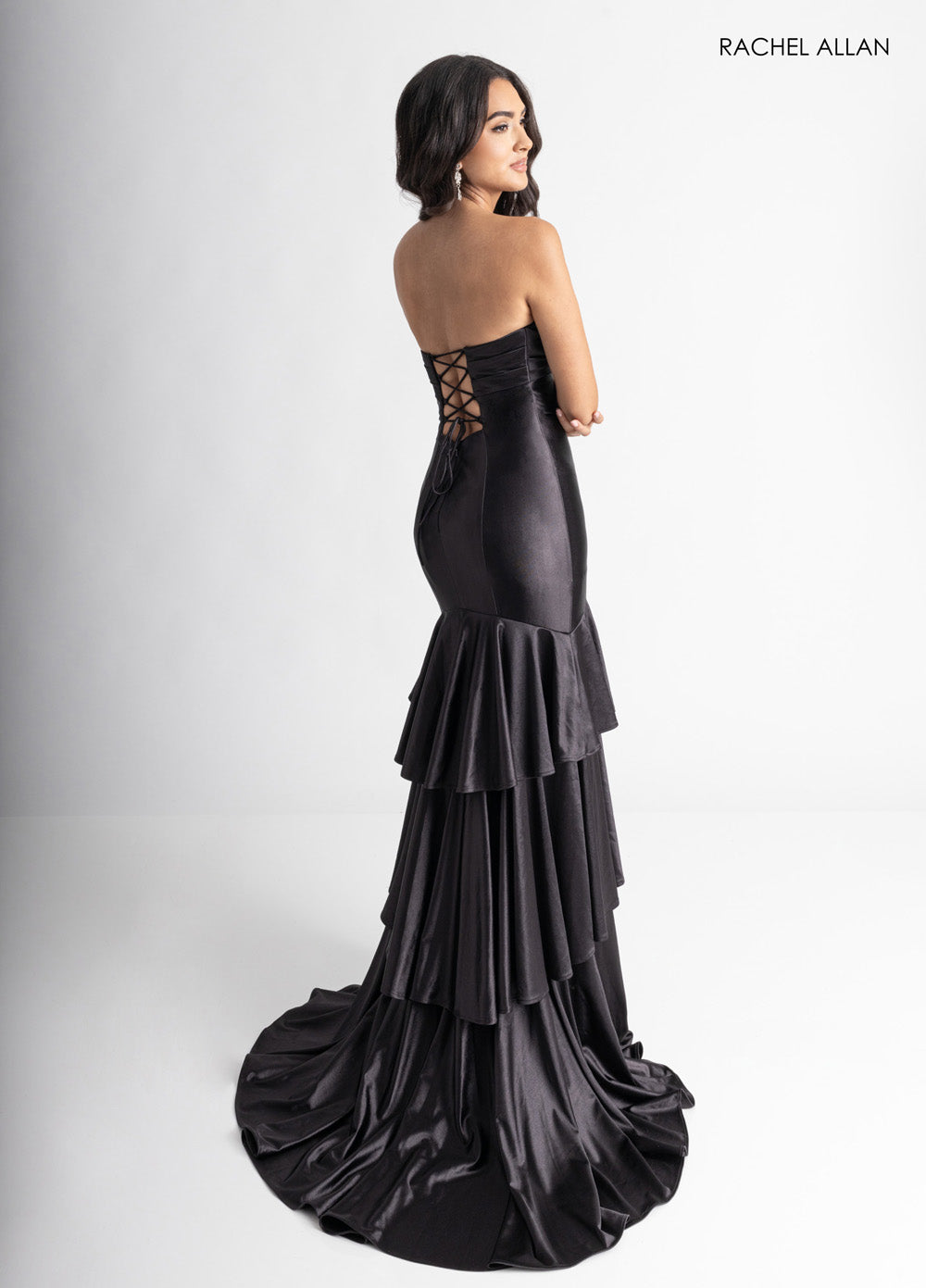 Rachel Allan 70987 Black mermaid prom dress with a lace-up back and layered ruffle hem.