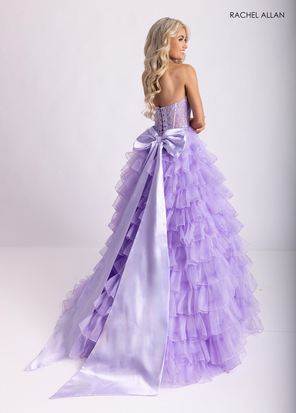Rachel Allan 71006 Lilac ballgown with ruffled layers and a satin bow, back view prom dress.