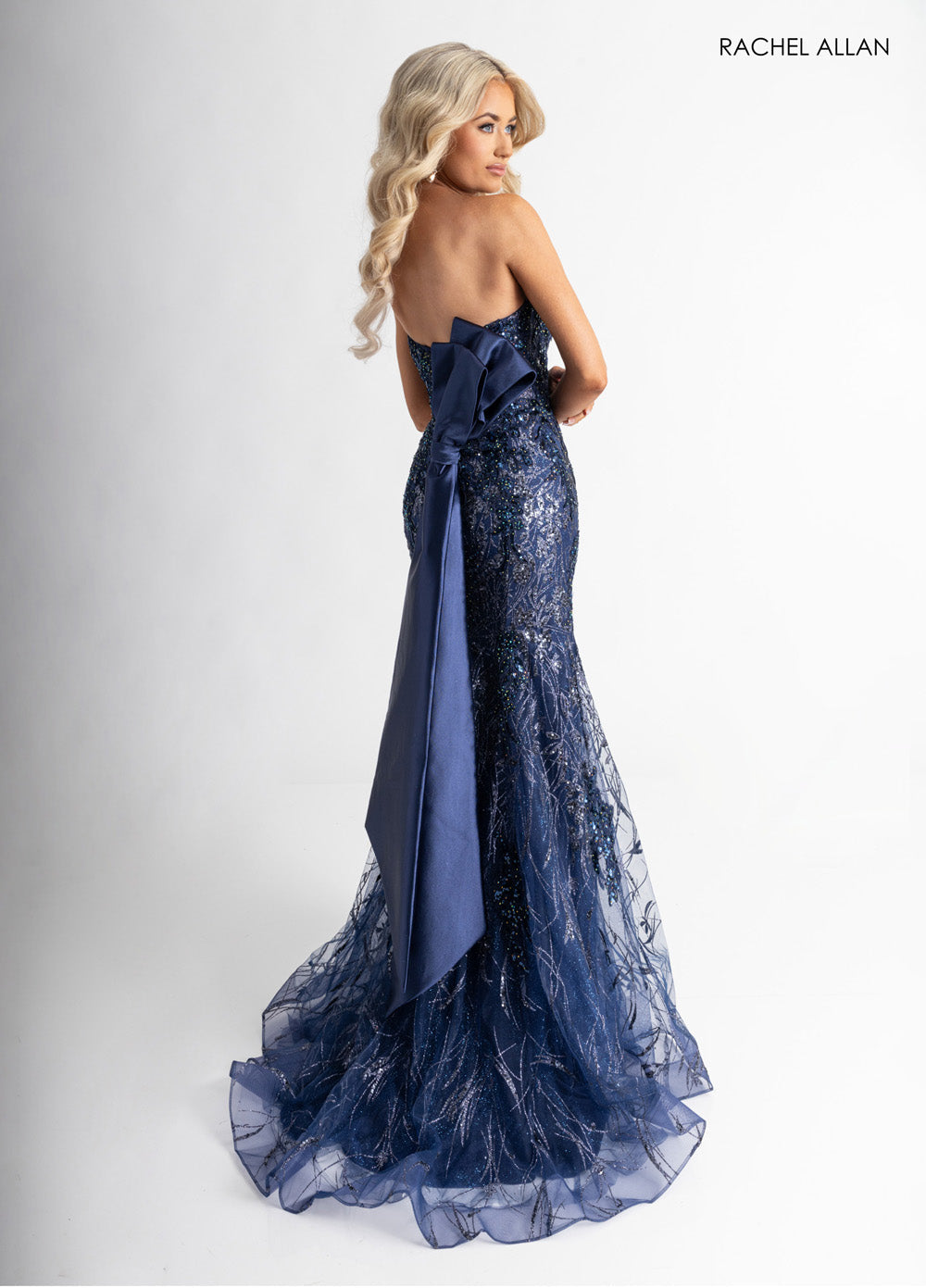 Rachel Allan 71008 Navy mermaid prom dress with crystal beading and a dramatic bow detail.