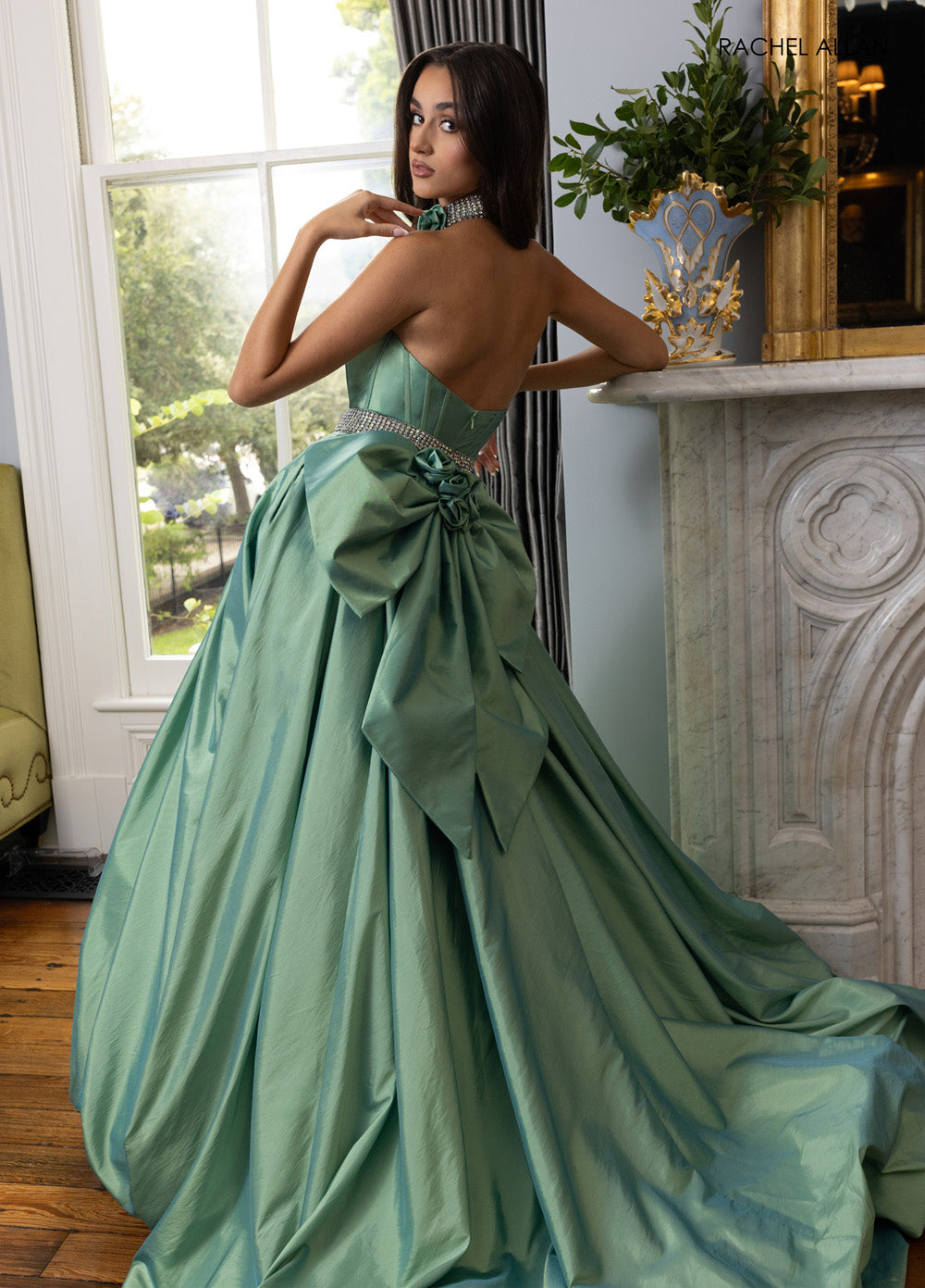 Rachel Allan 71024 Sage green formal gown with crystal beading and a dramatic bow, back view.
