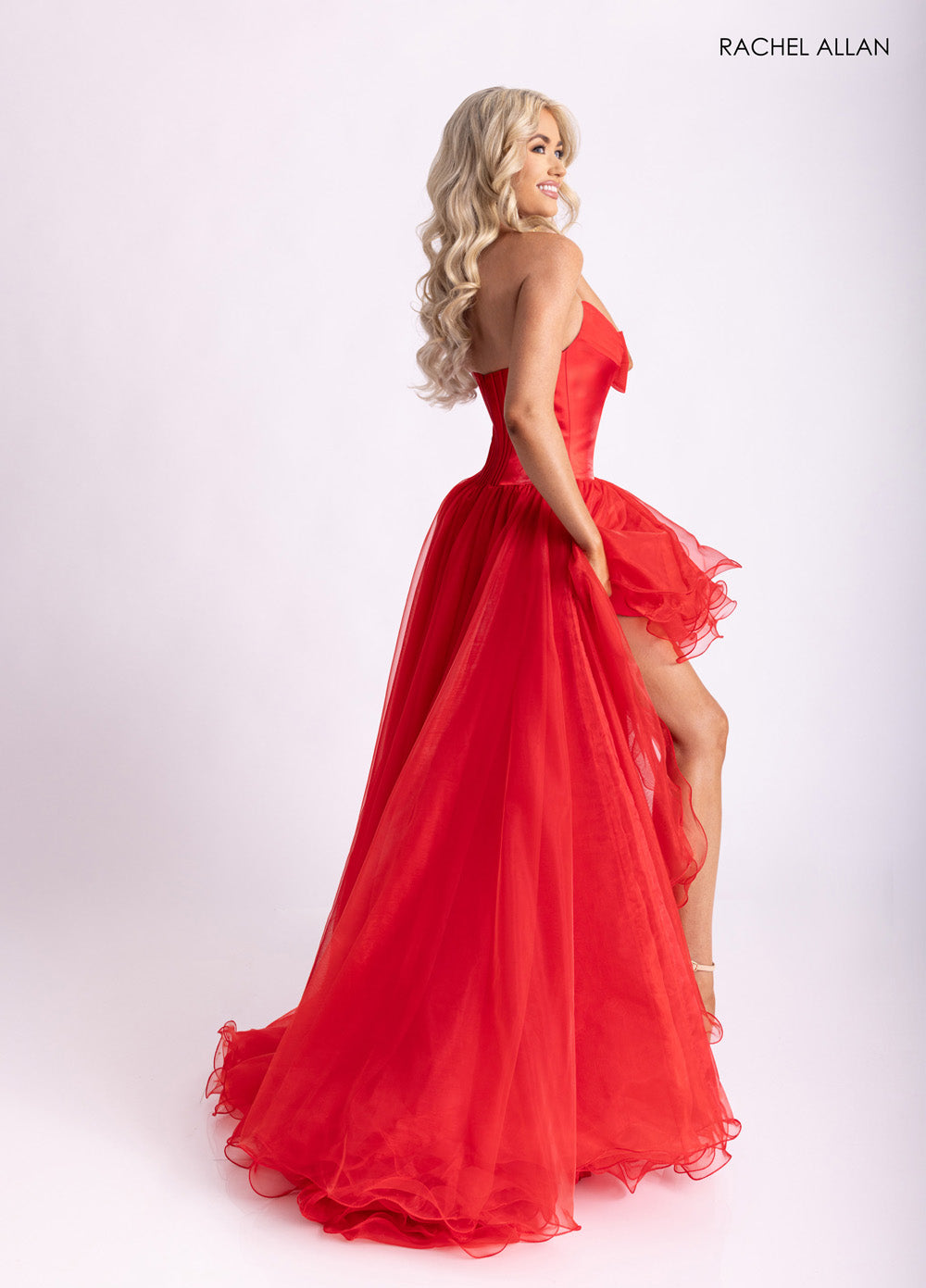 Rachel Allan 71046 Red A-line prom dress with a high slit and layered organza skirt, side view.