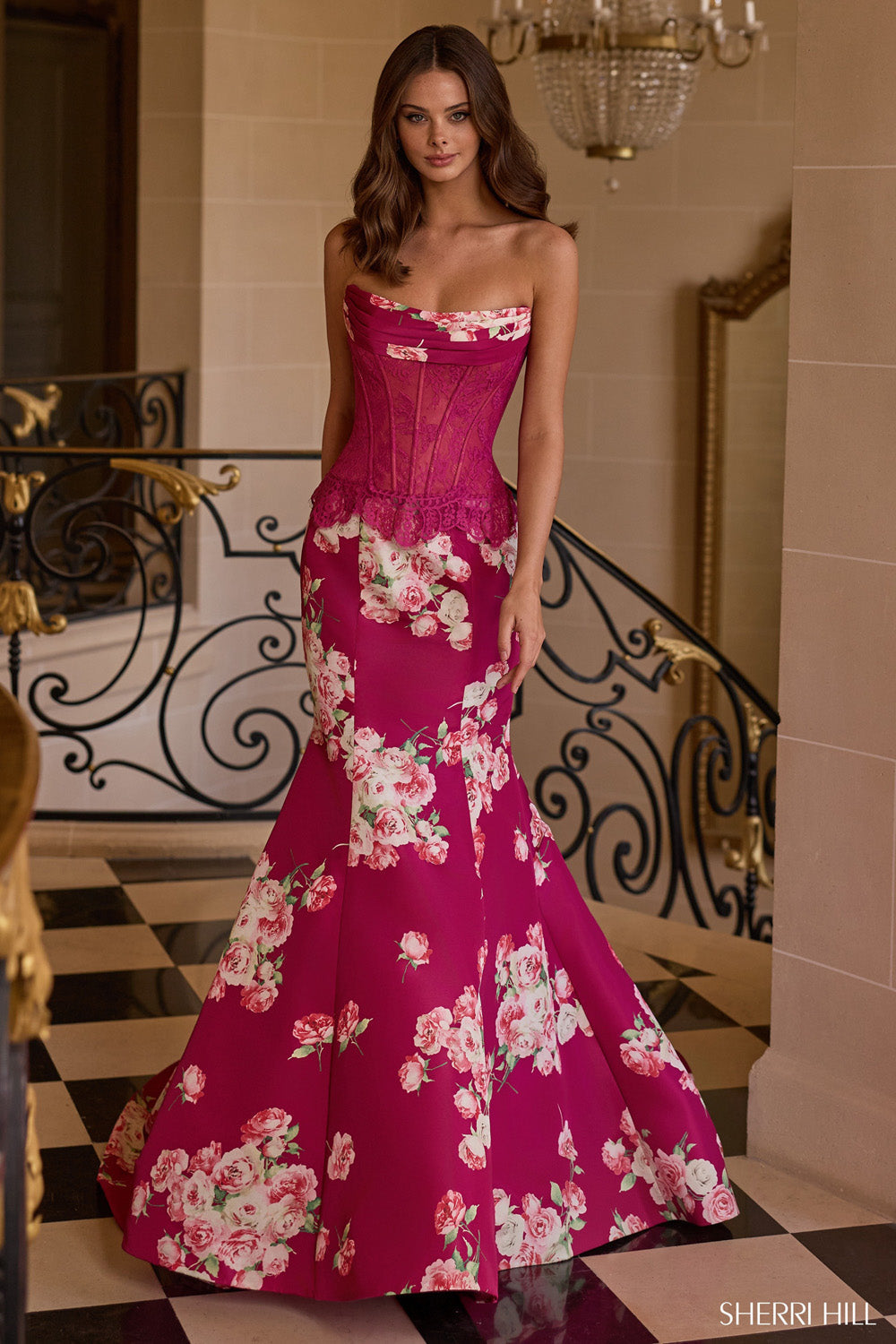 Sherri Hill 58180 plum floral mermaid gown with lace corset bodice and scalloped peplum, front view on grand staircase.