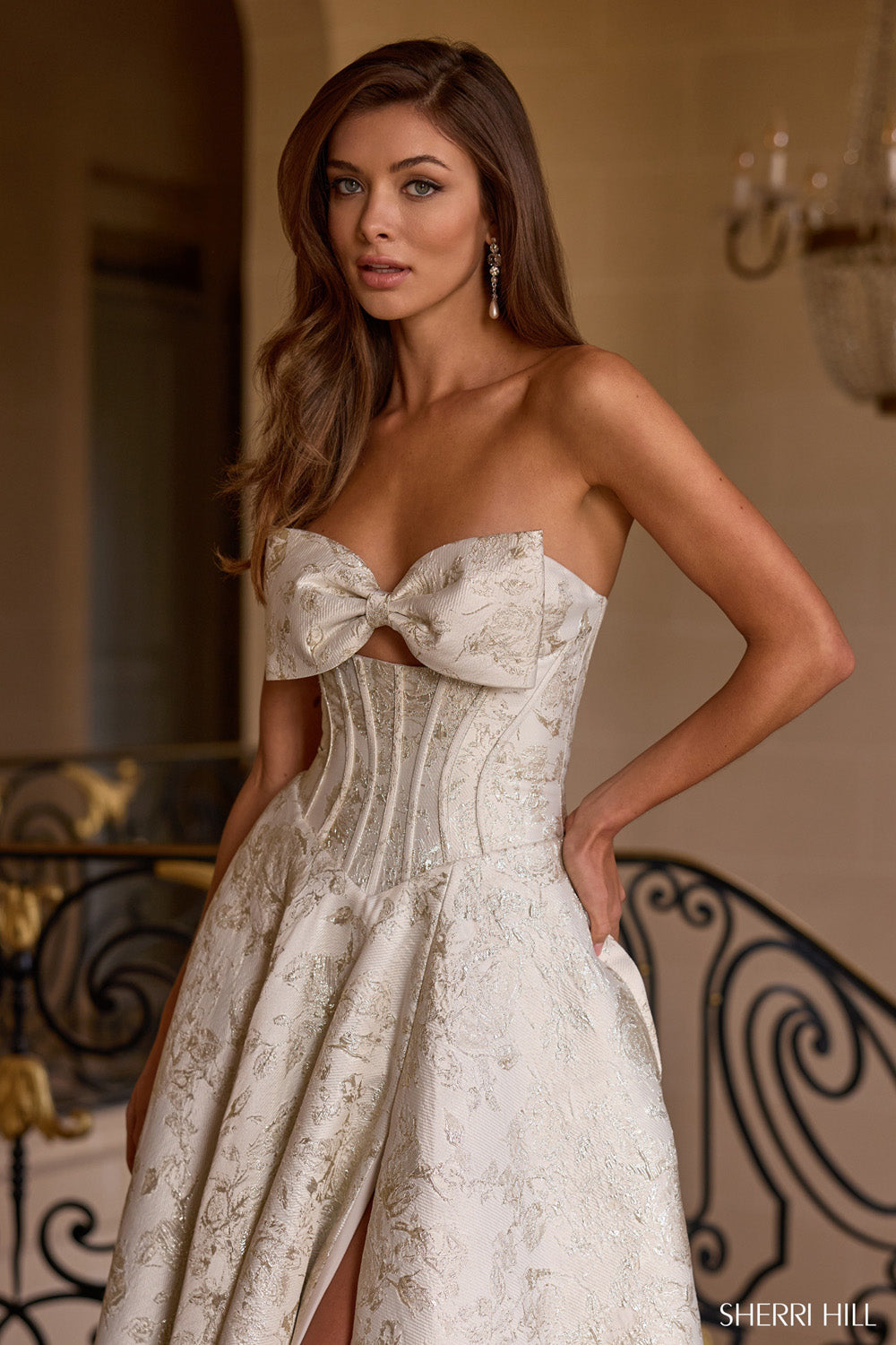 Close-up of Sherri Hill 58240 bow detail and sheer boned corset bodice in ivory and gold floral brocade fabric.