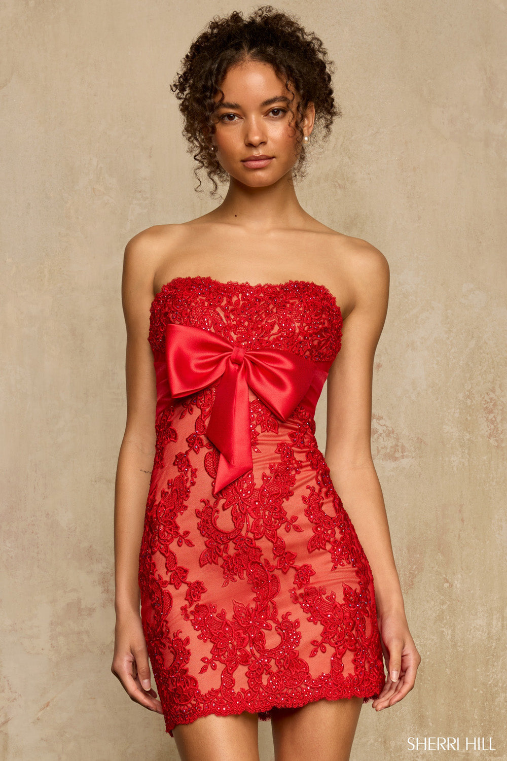 Front view of Sherri Hill 58268 red nude strapless lace cocktail dress with large satin bow at waist