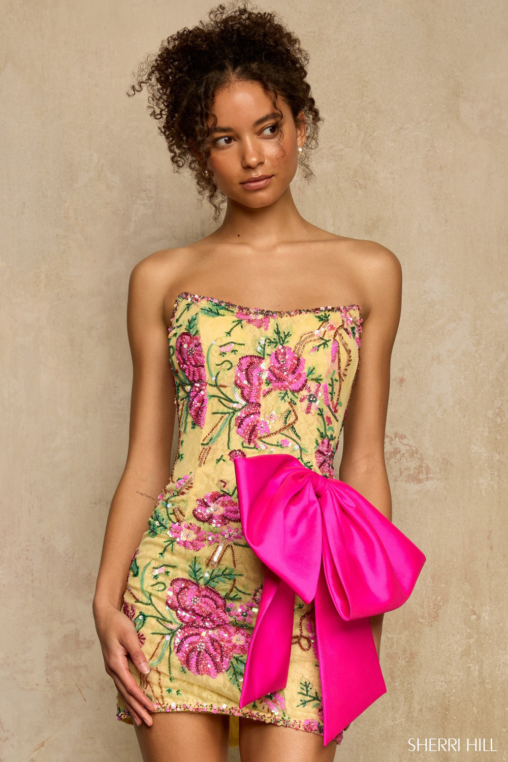 Sherri Hill 58300 yellow embroidered strapless homecoming dress with hot pink bow, three-quarter front view neutral background