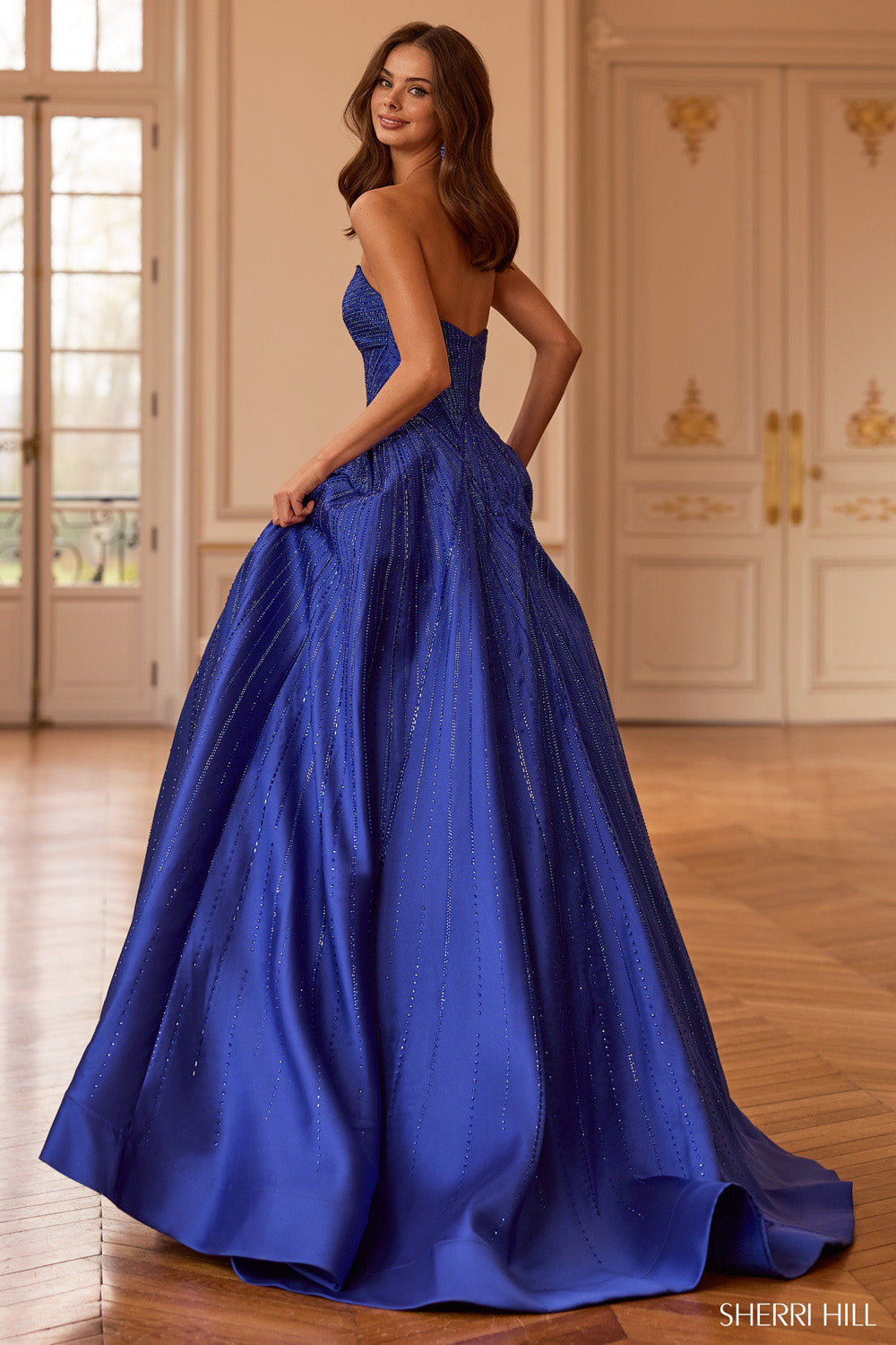 Sherri Hill 58327 royal blue ballgown, back view showing open back, cascading crystal-beaded skirt, and full train.