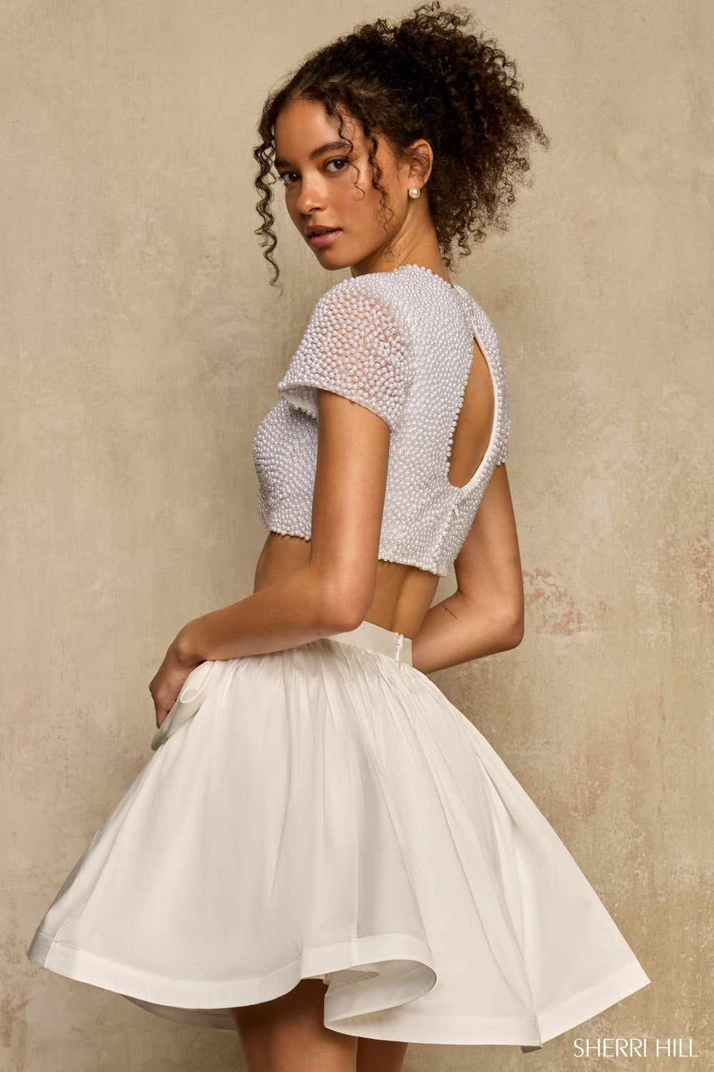 Back view of Sherri Hill 58370 ivory pearl crop top with keyhole cutout and full taffeta mini skirt with bow.
